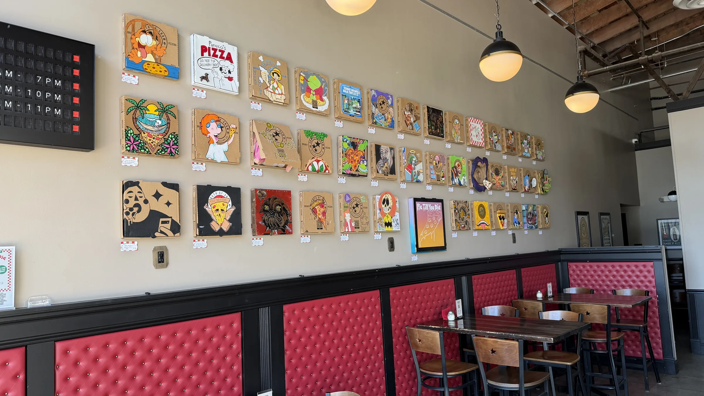 Forty artist-decorated pizza boxes displayed on the wall at South of Shaw.